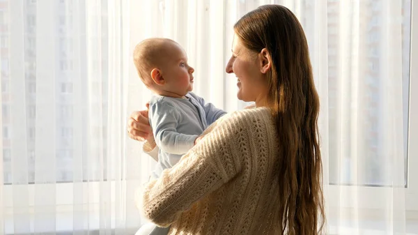 Słodkie dziecko patrząc na uśmiechniętą matkę na dużym darowiźnie w świetle zachodu słońca. Pojęcie szczęścia rodzinnego i rodzicielstwa — Zdjęcie stockowe