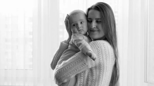 Feliz mãe sorridente segurando seu filhinho nas mãos e beijando na cabeça. Conceito de felicidade familiar e parentalidade — Fotografia de Stock