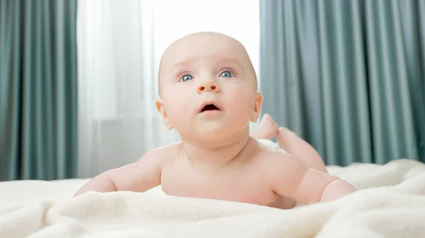 Adorable niñito acostado boca abajo y arrastrándose en la cama. — Foto de Stock