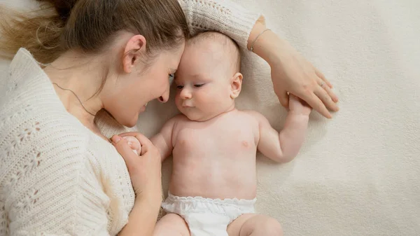 Closeup portrait of little baby with mother lying face to face on bed — Stock Photo, Image