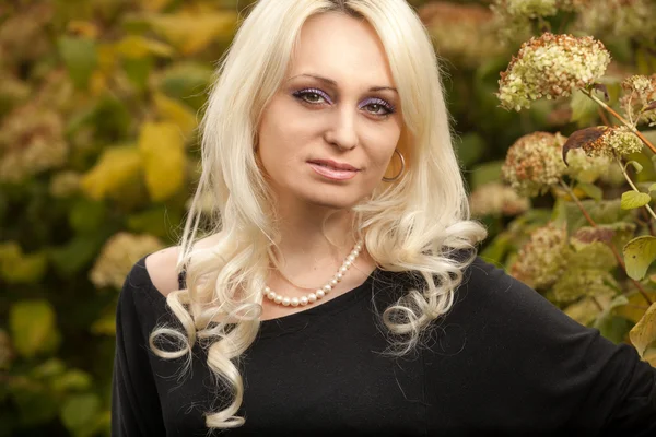 Elegante blonde vrouw die zich voordeed op de tuin van de herfst — Stockfoto