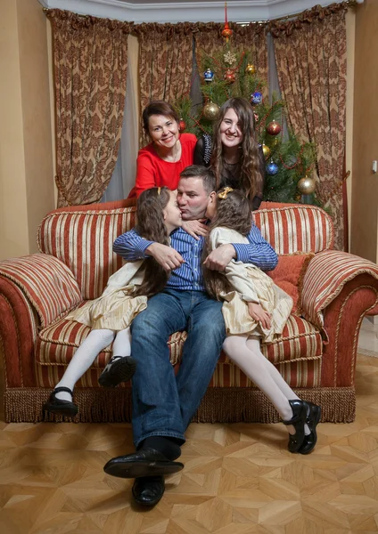 Father kissing daughters on sofa at christmas eve — Stock Photo, Image