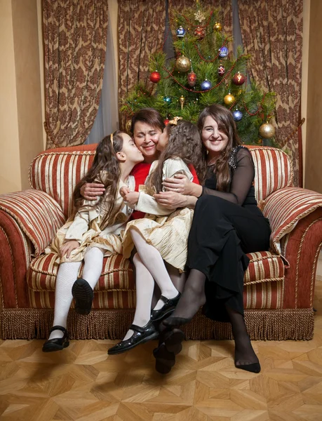 Happy daughters sitting on sofa with mother at christmas — Stock Photo, Image