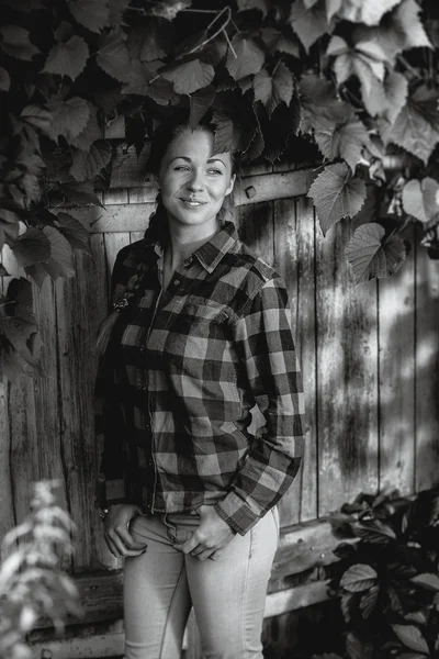 Retrato monocromático de menina sorridente inclinando-se contra ba overgrown — Fotografia de Stock