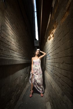 iki yüksek tuğla binalar arasında duran genç kadın