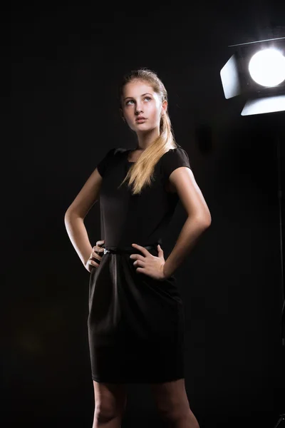 Beautiful blonde girl against light equipment at studio — Stock Photo, Image