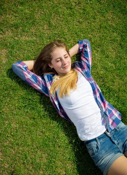 Genç kız güneşli bir gün geri çim üzerinde yalan — Stok fotoğraf