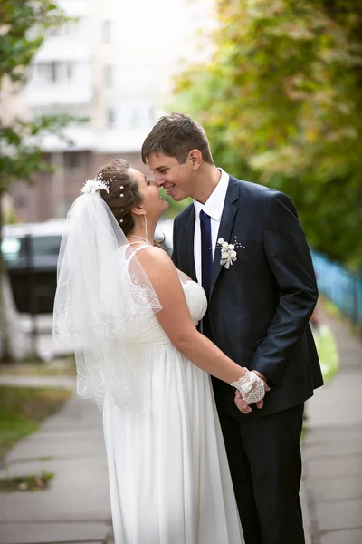 Bride and groom looking at each other and hugging on street — Stock Photo, Image