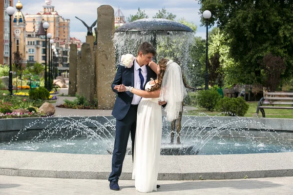 Невеста и жених танцуют возле фонтана в парке — стоковое фото