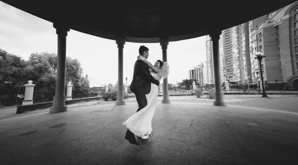 Monochrome shot of bride and groom dancing at alcove in park — Stock Photo, Image