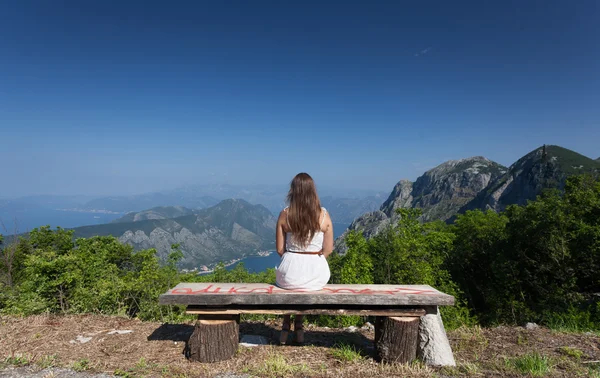 Brunette woman sitting on bench at high mountain — Stock Photo, Image