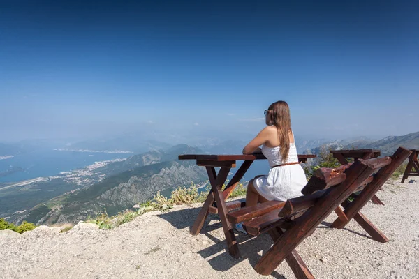 Woman siting on bench on top of mountain and looking at landscap — Stock Photo, Image