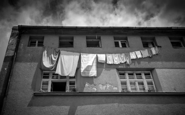 Monochrome photo of clothes drying outside of grungy building — Stock Photo, Image