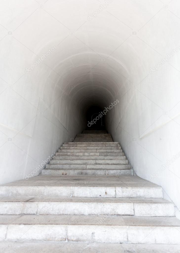 marble staircase leading to dark tunnel