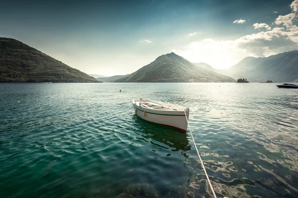 Witte roeiboot afgemeerd aan baai omringd door bergen — Stockfoto