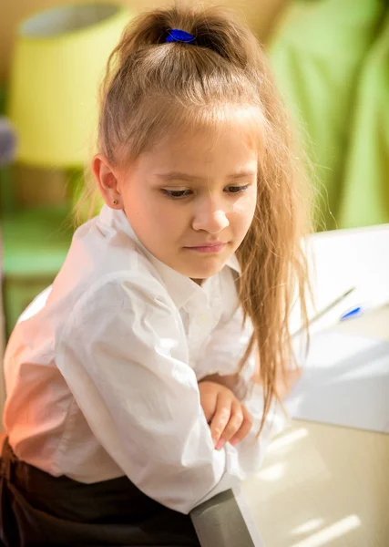 Chica cansada en uniforme escolar sentado en el escritorio con la tarea —  Fotos de Stock