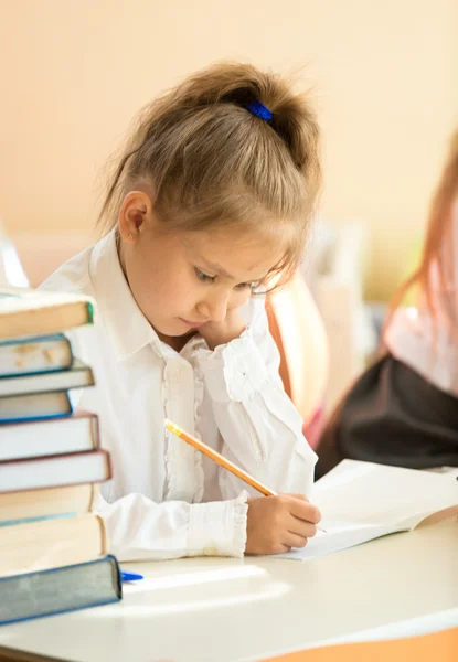 Ritratto di ragazza triste esercizio di scrittura in un libro di testo una scuola — Foto Stock