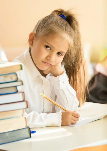 Muchacha molesta prueba de escritura en el aula y mirando la cámara — Foto de Stock