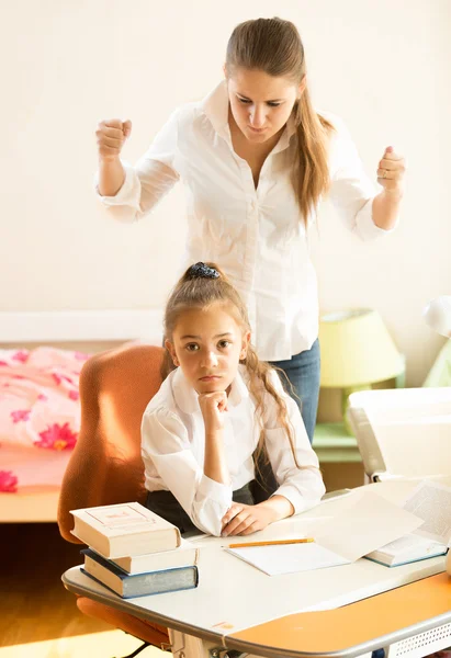 Mãe zangada jura na filha fazendo lição de casa — Fotografia de Stock