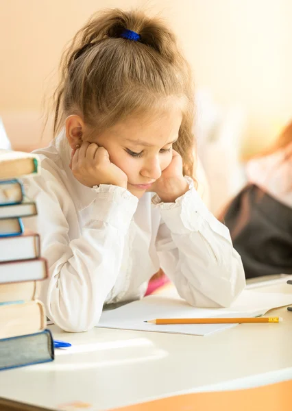 Portrait of upset schoolgirl looking at textbook with homework Stock Picture