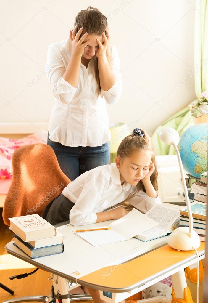 young mother looking daughter sleeping while doing homework