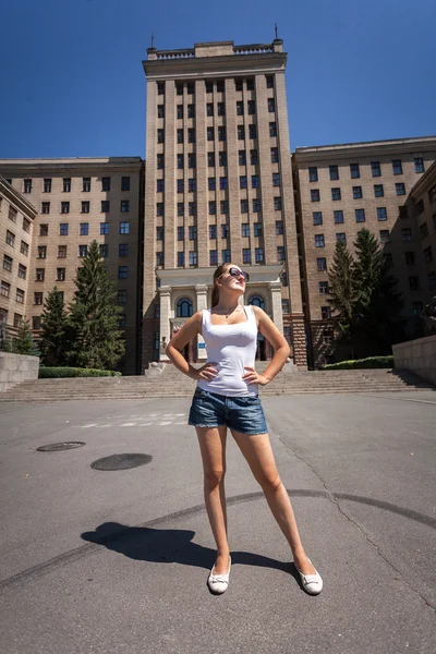 Wanita langsing berdiri di jalan terhadap bangunan tinggi — Stok Foto