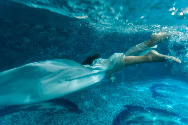 Bela mulher vestindo tecido branco mergulho na piscina — Fotografia de Stock