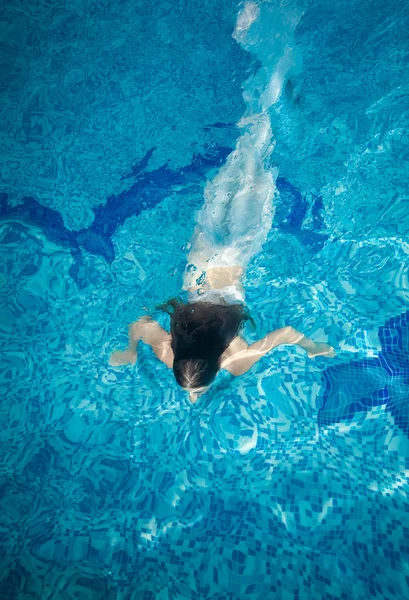 Vrouw bedekt in lange witte stof zwemmen onder water op zwembad — Stockfoto