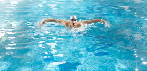 Handsome athlete swimming in poll at butterfly style — Stock Photo, Image