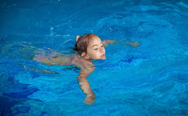 Girl trying to hold on water surface at swimming pool — Stock Photo, Image