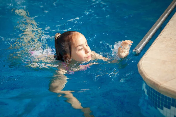 Mädchen schwimmt an den Rand des Schwimmbades — Stockfoto