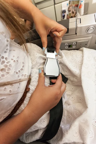 Woman fastening seat belt at airplane — Stock Photo, Image