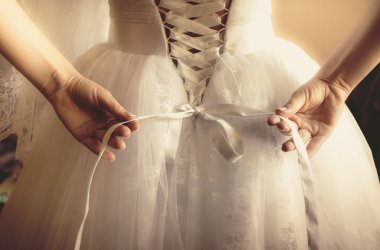 toned photo of beautiful bride tying up her wedding dress clipart