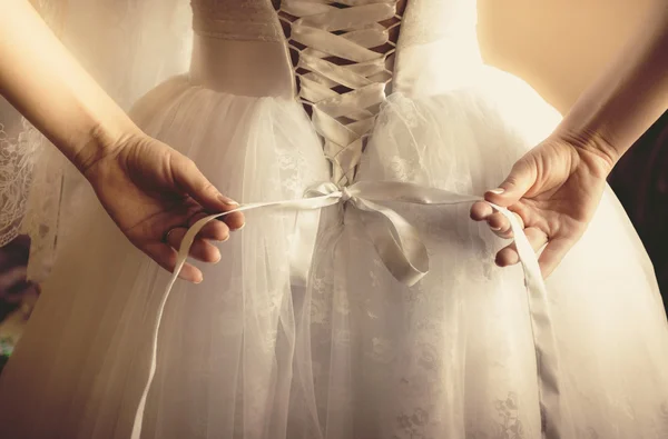 Foto tonica di bella sposa legando il suo abito da sposa — Foto Stock