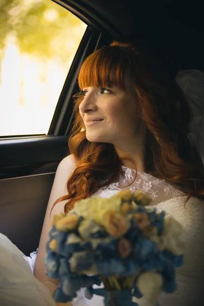 Портрет улыбающейся рыжей невесты, смотрящей в окно на автомобиль — стоковое фото