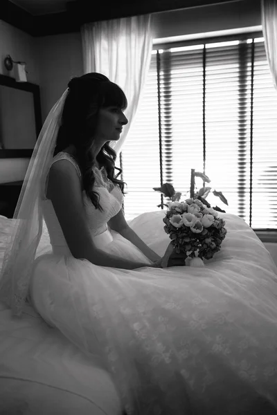 Портрет красивой невесты, сидящей на кровати в доме — стоковое фото