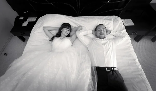 Retrato de la novia y el novio tumbado en una cama grande en el hotel —  Fotos de Stock