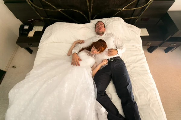 Married couple lying on big bed at hotel — Stock Photo, Image