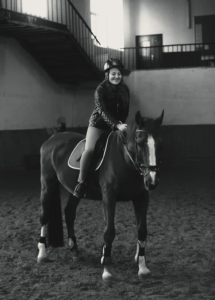 Монохромное фото красивой женщины верхом на лошади в манеже — стоковое фото