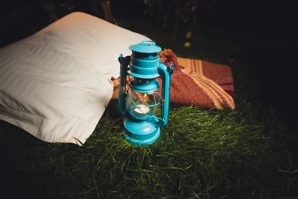 Old lantern, pillow and blanket lying on grass at night — Stock Photo, Image