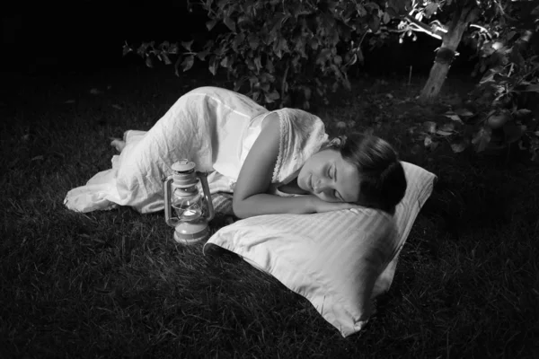 Foto monocromática de la mujer durmiendo en el jardín por la noche — Foto de Stock