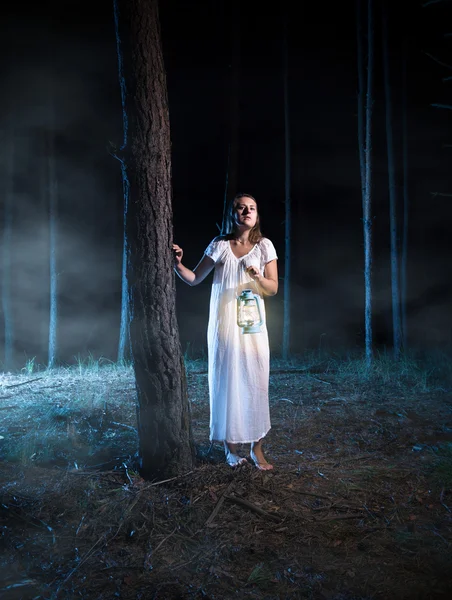 Scared woman walking in foggy night forest with lantern — Stock Photo, Image