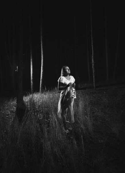 Monochrome photo of woman in white dress walking at forest at ni