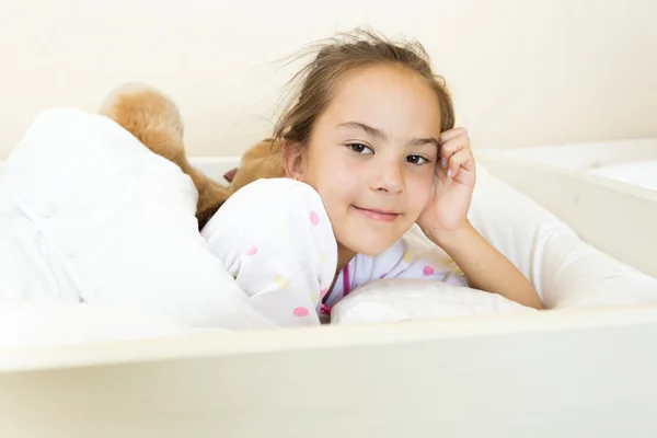 Liten brunett flicka vaknade vid säng på morgonen — Stockfoto