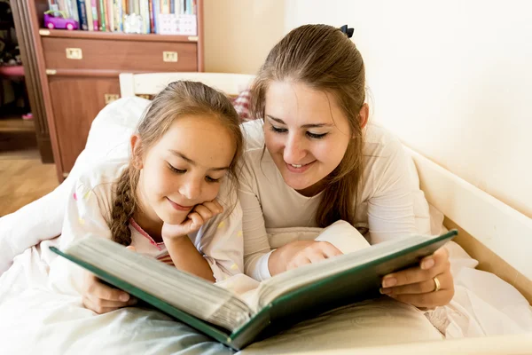 Ung mamma och dotter i sängen och Visa fotoalbum — Stockfoto