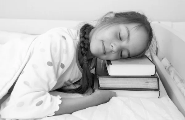 Monochrome portrait of little girl sleeping on pile of books at — Stock Photo, Image