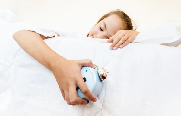 Kleines Mädchen schläft und hält Wecker in der Hand — Stockfoto