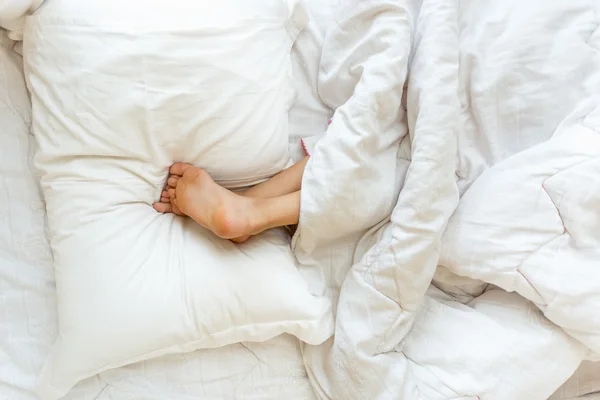 Little girl sleeping upside down and holding feet on pillow — Stock Photo, Image