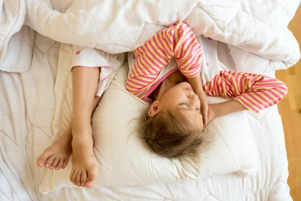 Little girl and sisters feet on pillow at bed — Stock Photo, Image