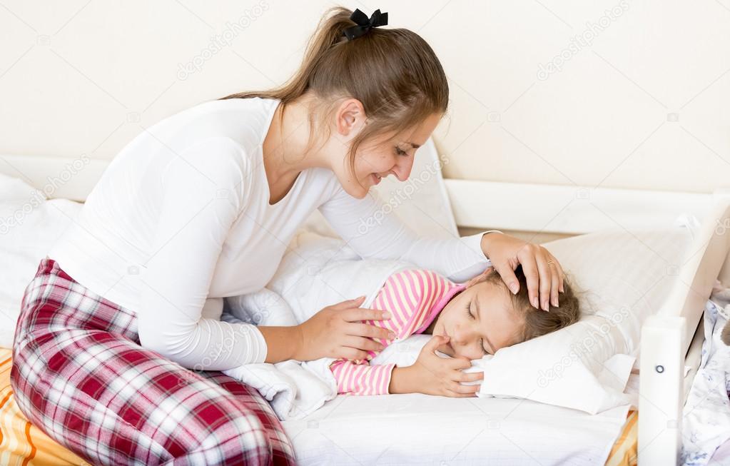 brunette mother waking up sleeping daughter at morning